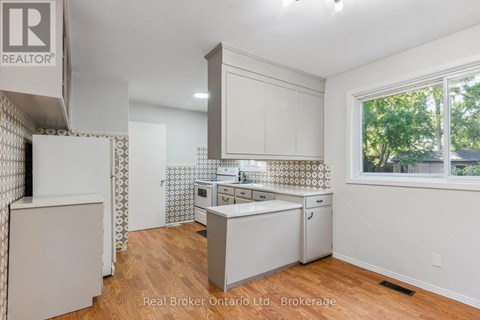 A kitchen with white cabinets and a wooden floor.