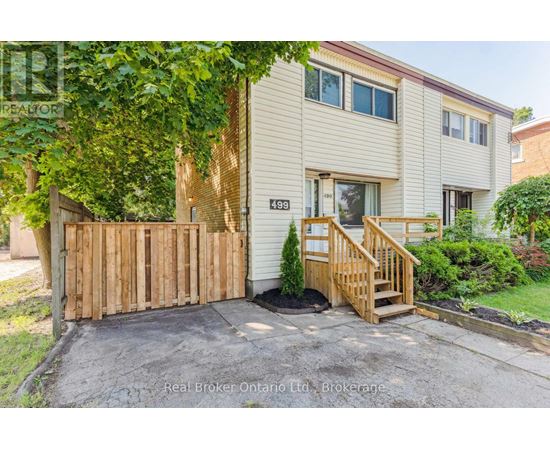 A house with a wooden fence and a small tree in front.