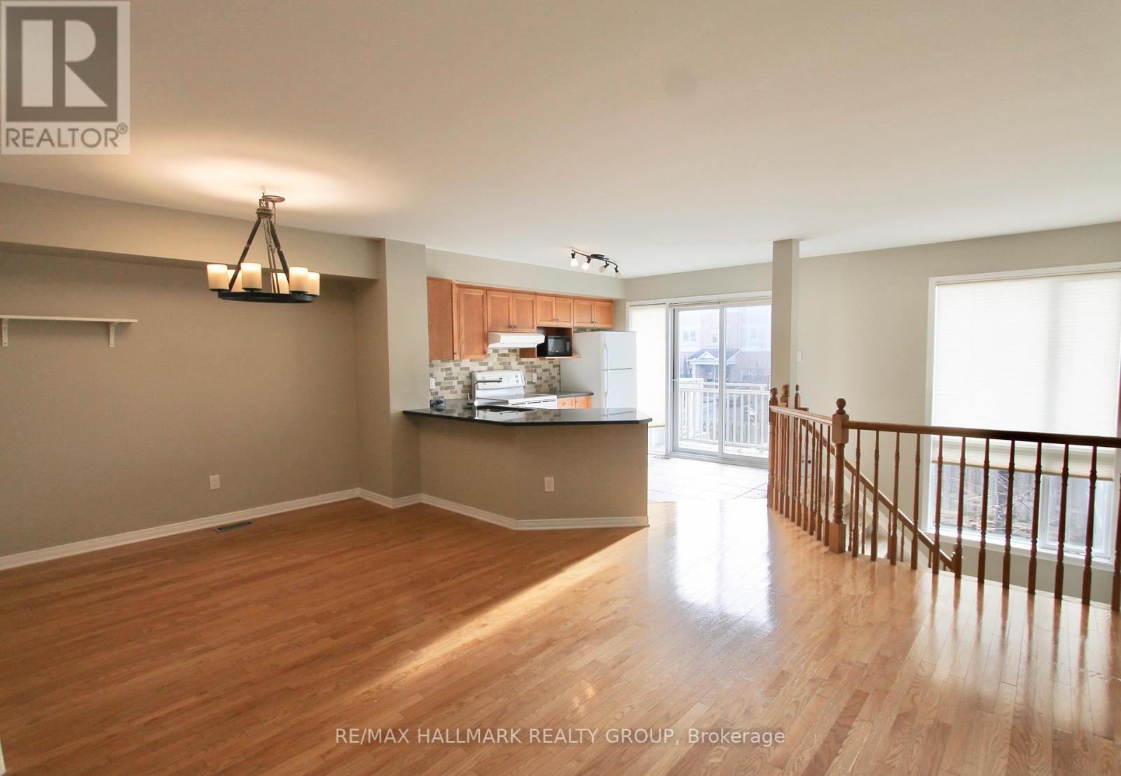 A spacious room with wooden flooring and a kitchenette in the background.