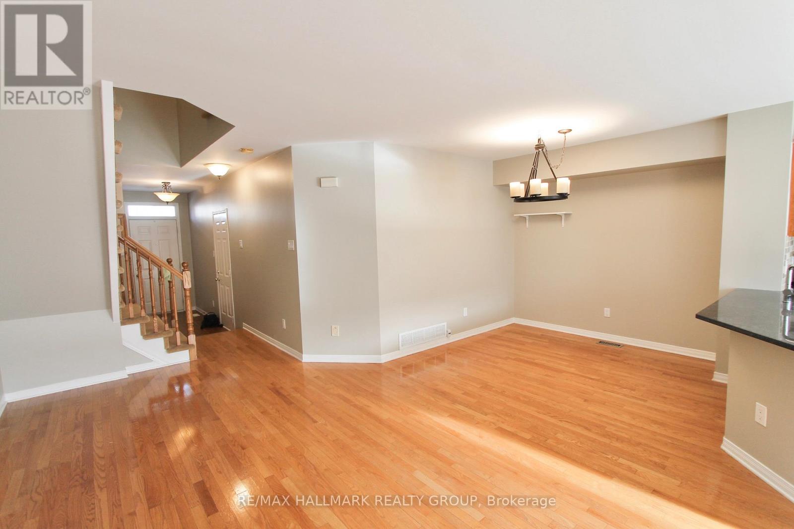 A room with wooden floors and a staircase leading to another room.