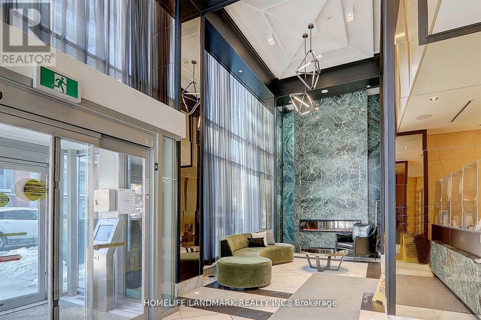 A modern office lobby with a glass wall and a green sofa.