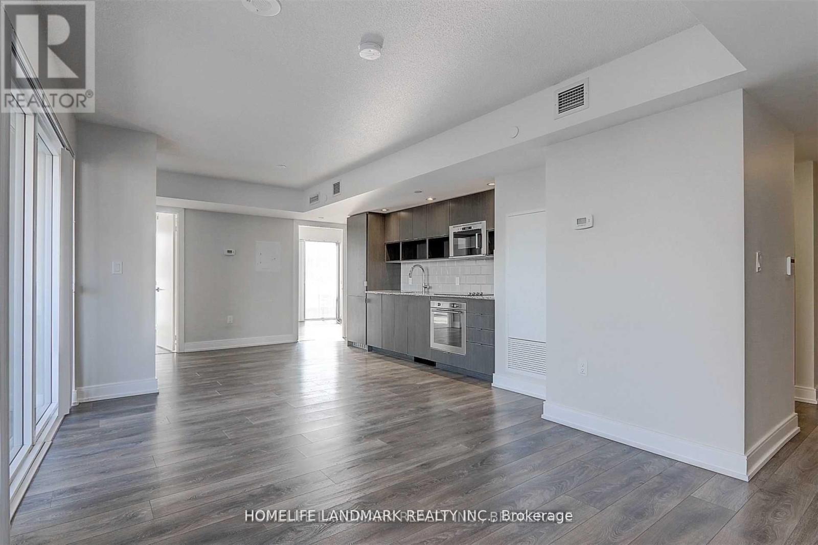 A spacious living room with a kitchen area in the background.