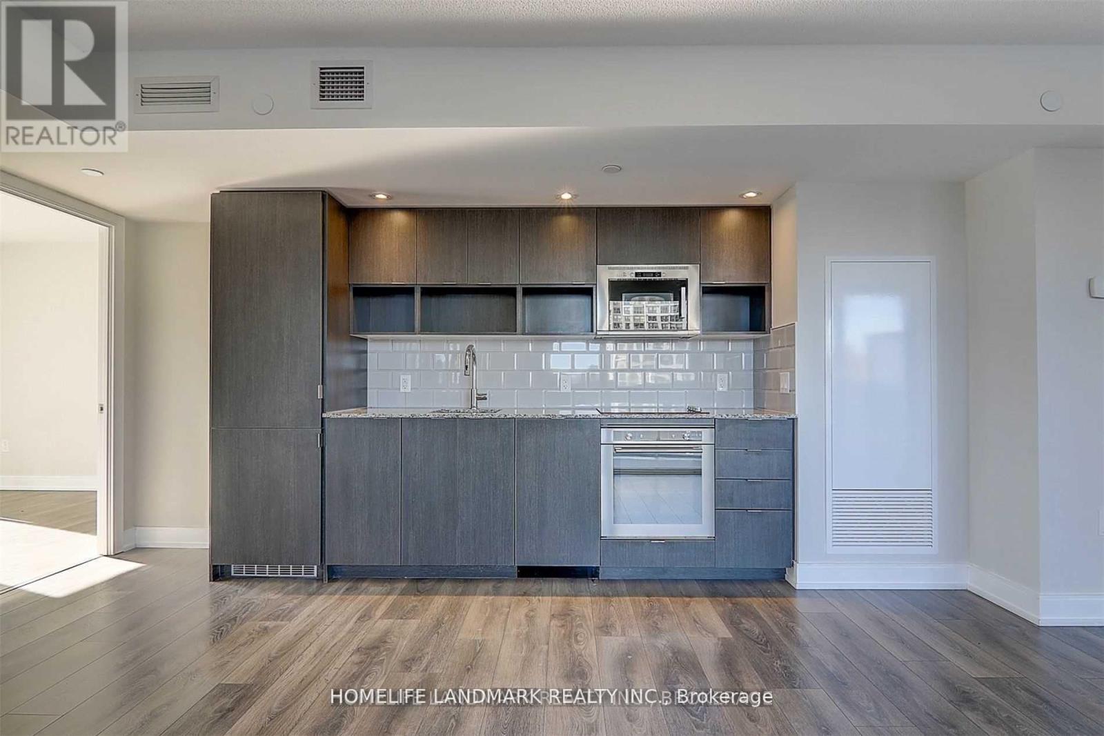 A modern kitchen with dark wood cabinets and a stainless steel oven.