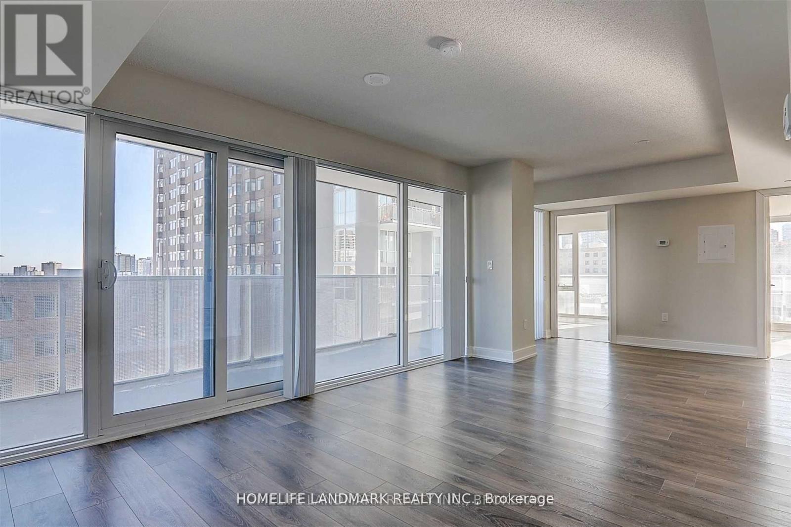 A spacious room with wooden floors and large windows overlooking a cityscape.