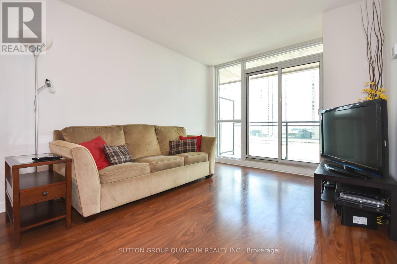 A living room with a tan couch and a black television.