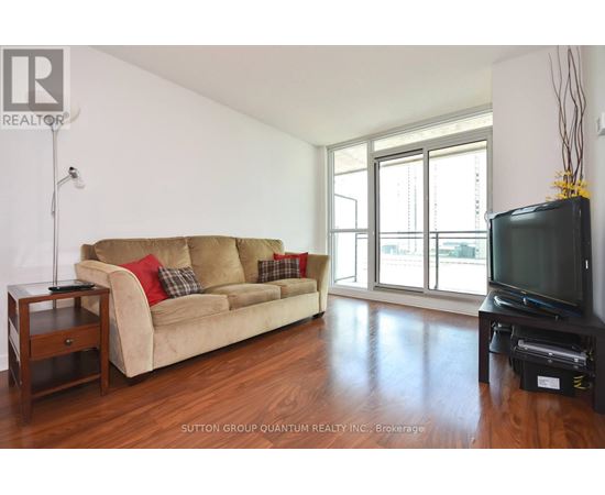 A living room with a tan couch and a black television.