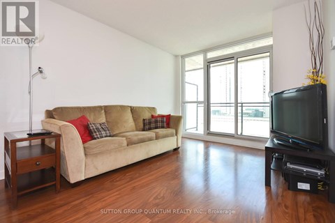 A living room with a tan couch and a black television.