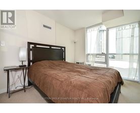 A bedroom with a large bed and a window overlooking a cityscape.