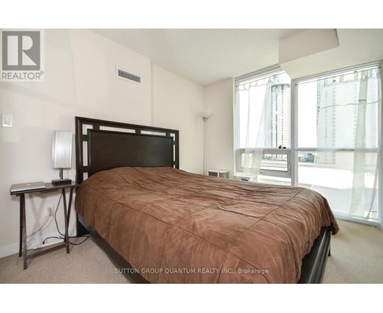 A bedroom with a large bed and a window overlooking a cityscape.