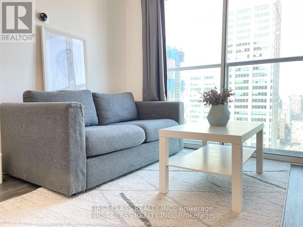 A grey couch and a white coffee table in a room with a large window.