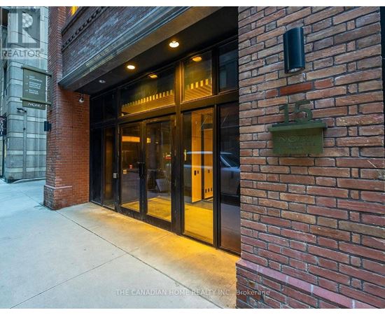 The entrance to a building with a glass door and a brick wall.