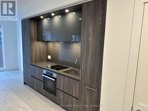 A modern kitchen with dark wood cabinets and stainless steel appliances.