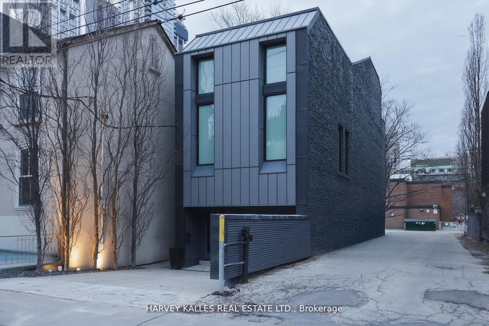 A modern house with a black facade and a garage door is shown.