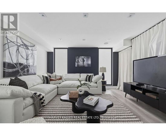 A modern living room with a white sofa set and a black and white abstract painting on the wall.