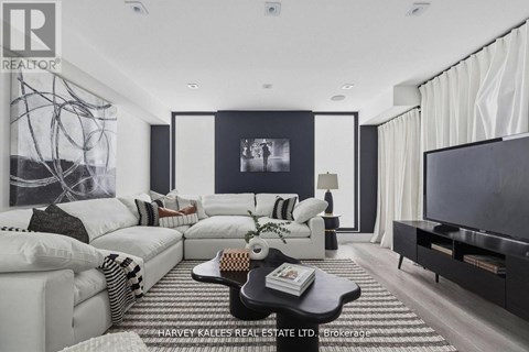 A modern living room with a white sofa set and a black and white abstract painting on the wall.