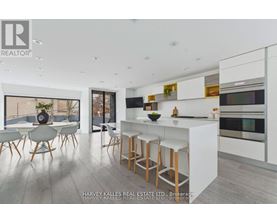 A modern kitchen with white cabinets and a bar area.