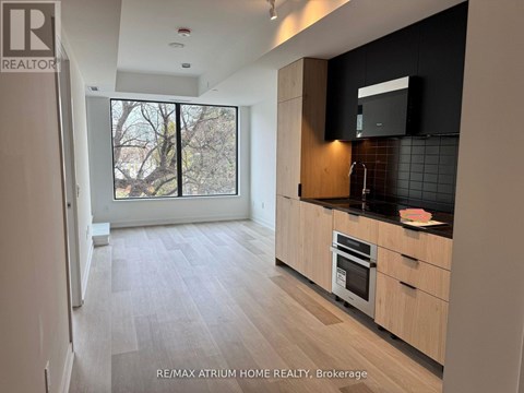 A kitchen with wooden floors and cabinets, a microwave, and a window.