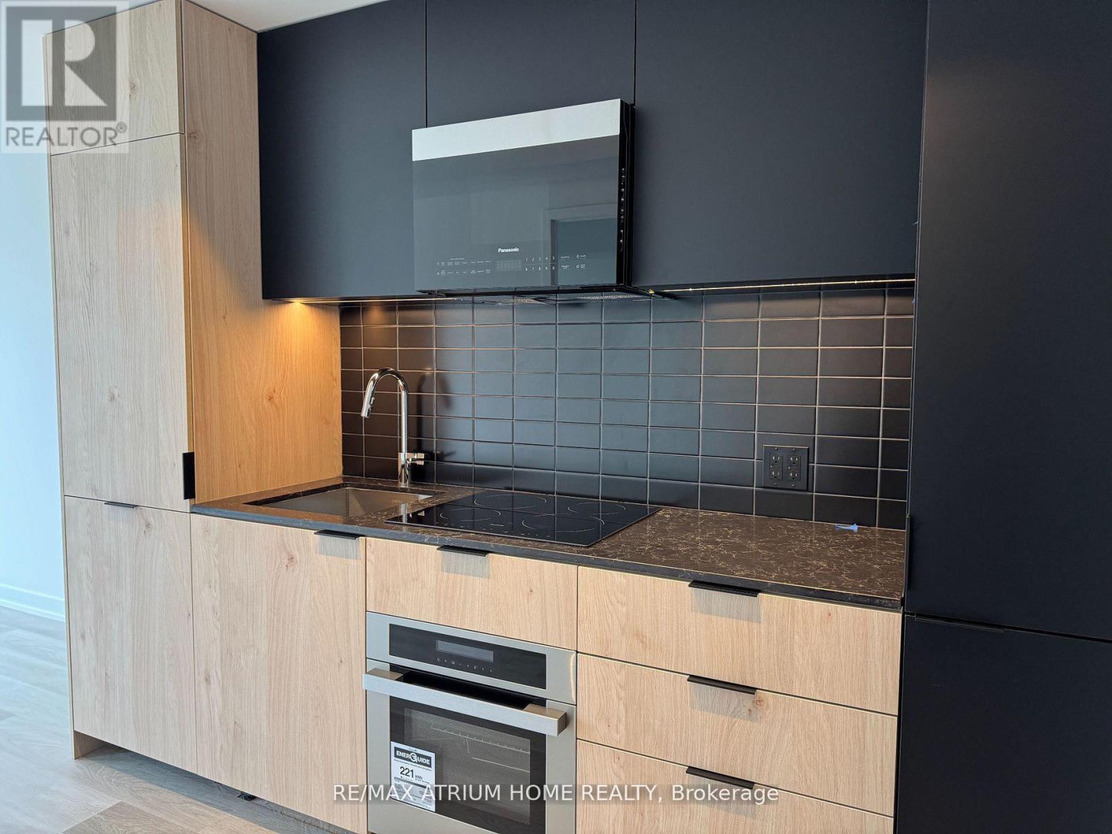 A modern kitchen with a black countertop and wooden cabinets.