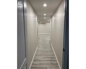 A hallway with a wooden floor and white walls.