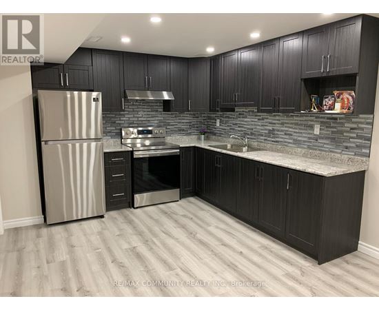 A kitchen with black cabinets and a stainless steel refrigerator.