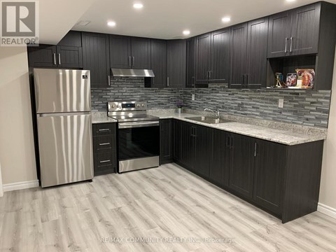 A kitchen with black cabinets and a stainless steel refrigerator.