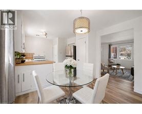 A modern dining room with a glass table and white chairs.