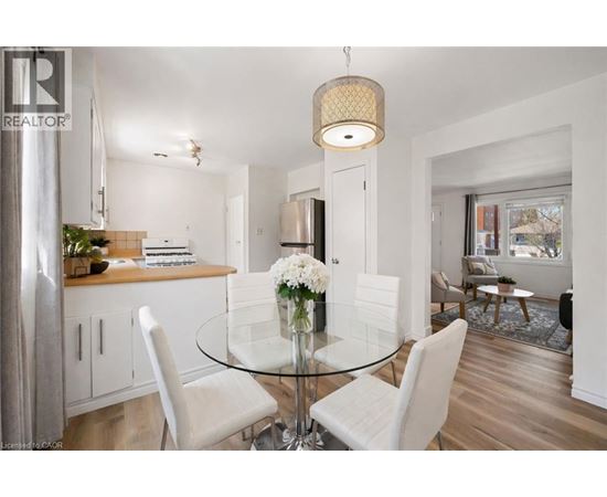 A modern dining room with a glass table and white chairs.