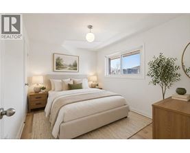 A bedroom with a large bed, a nightstand with a lamp, and a framed picture on the wall.