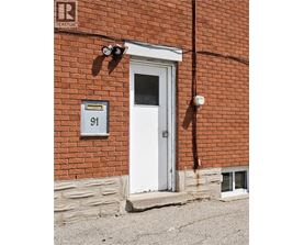 A red brick building with a white door and a sign that says 91.