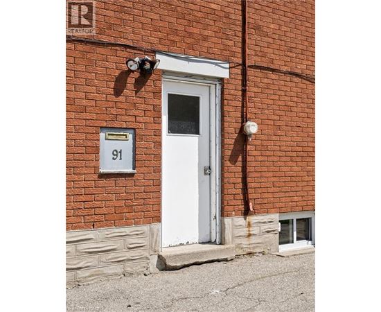 A red brick building with a white door and a sign that says 91.