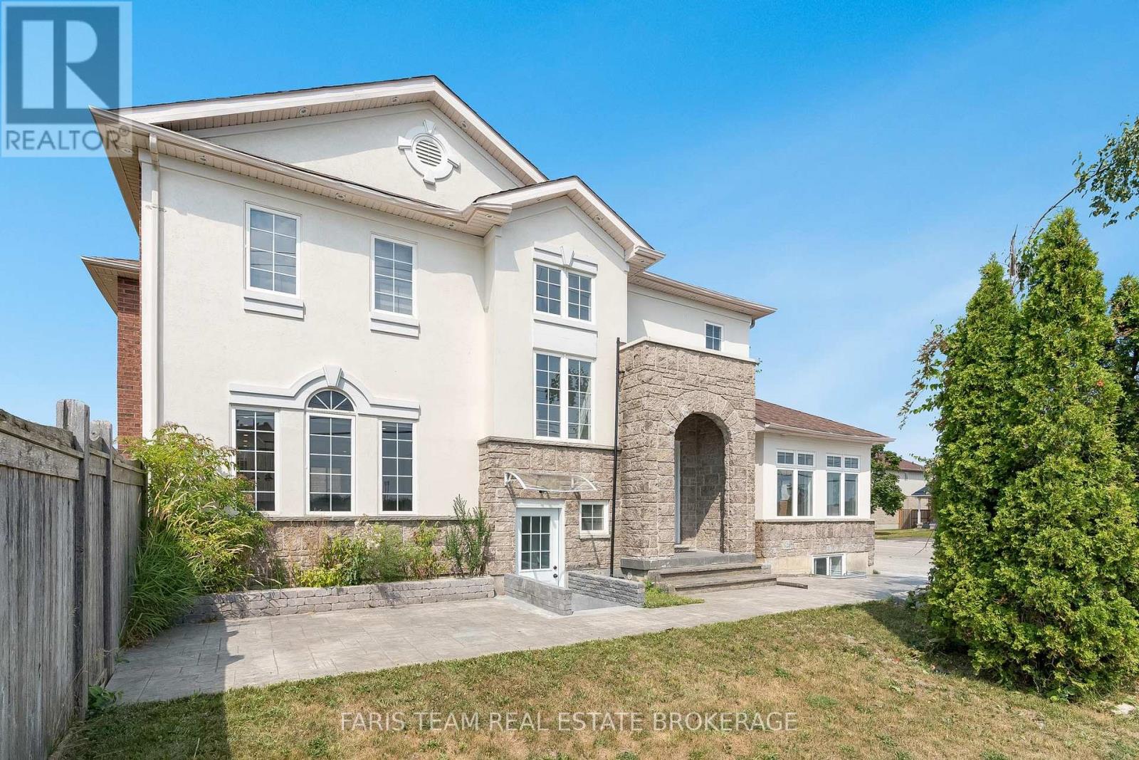 A large, two-story house with a stone archway entrance and a brick chimney.