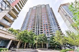 A tall residential building stands in the middle of a tree-lined street.