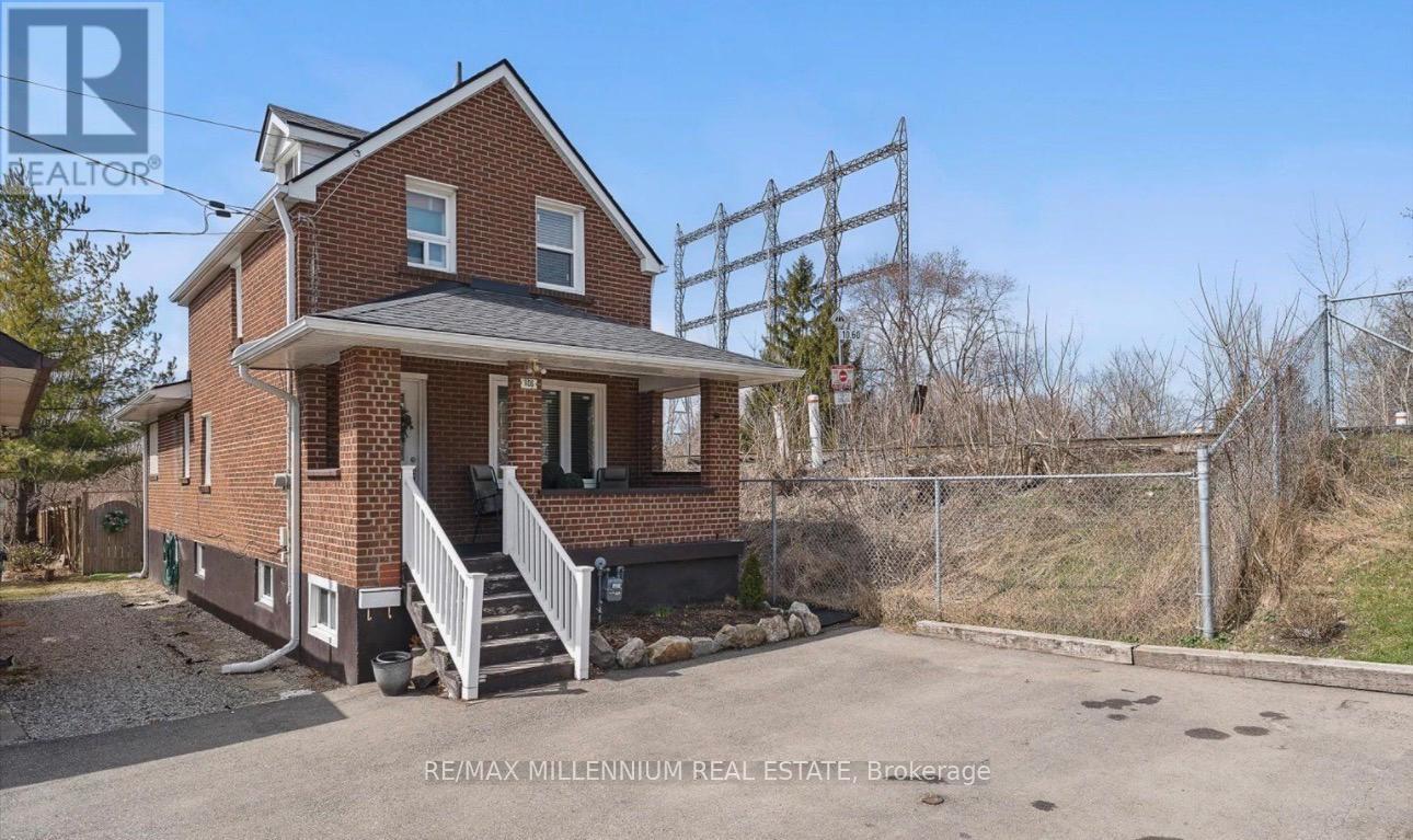 A brick house with a white porch and a sign that says RE/MAX Millennium Real Estate Brokerage.