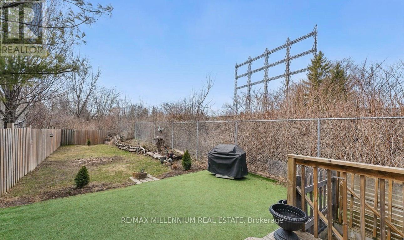 A backyard with a fence, a hot tub, and a deck.