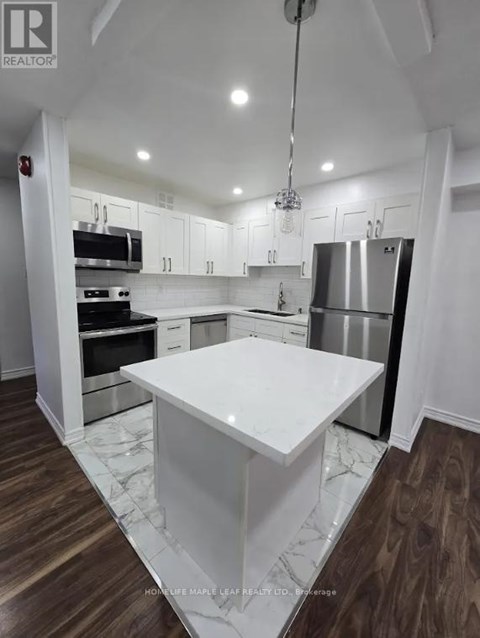 A modern kitchen with a white marble island and stainless steel appliances.