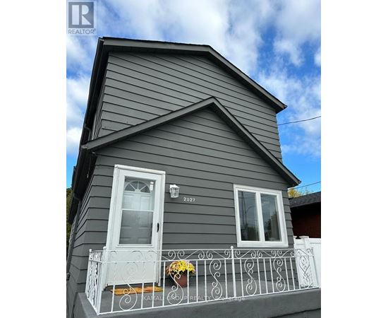 A grey house with a white door and window.