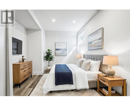 A well-lit bedroom with a bed, nightstand, and a plant.