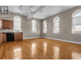 A spacious room with wooden floors and arched windows.