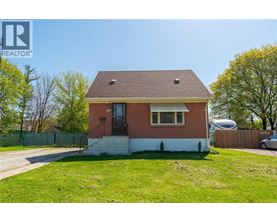 A small red brick house with a white front yard.