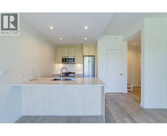 A modern kitchen with white cabinets and a wooden floor.