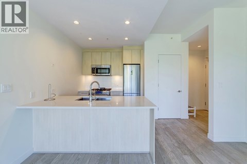 A modern kitchen with white cabinets and a wooden floor.