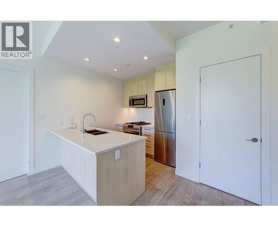 A kitchen with a white countertop and a stainless steel refrigerator.