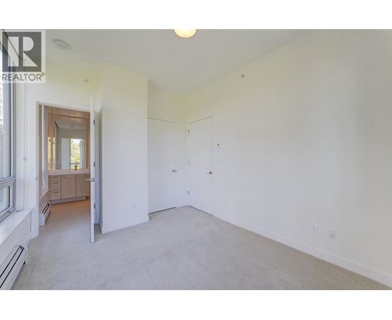 A spacious room with white walls and a carpeted floor.