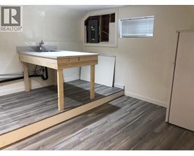 A room with a wooden table and a window with blinds.