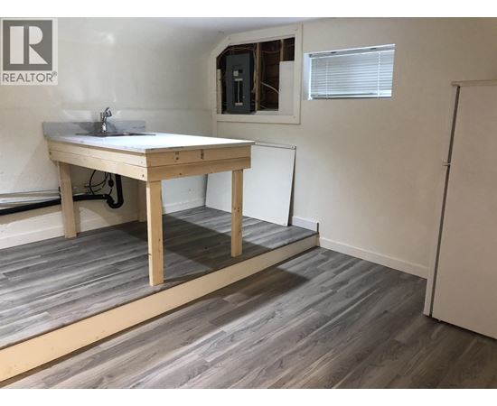 A room with a wooden table and a window with blinds.