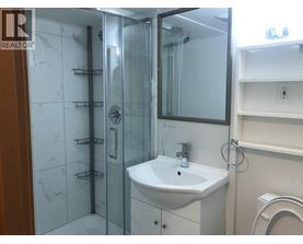 A white sink in a bathroom with a glass shower door.