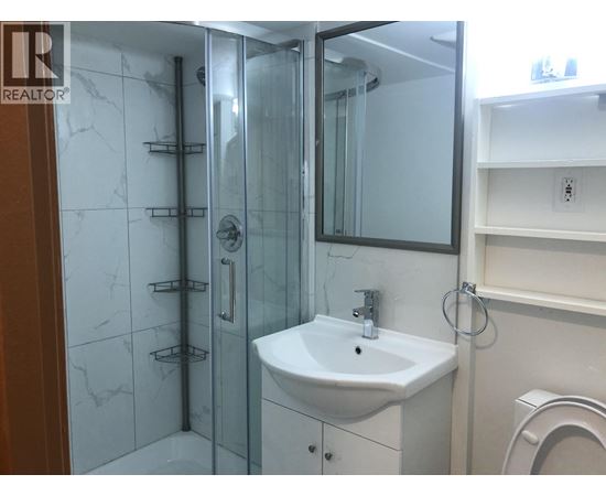 A white sink in a bathroom with a glass shower door.