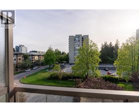 A view from a balcony overlooking a street with cars and buildings.