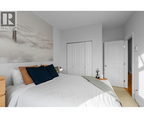 A bedroom with a large bed and a realtor sign on the wall.