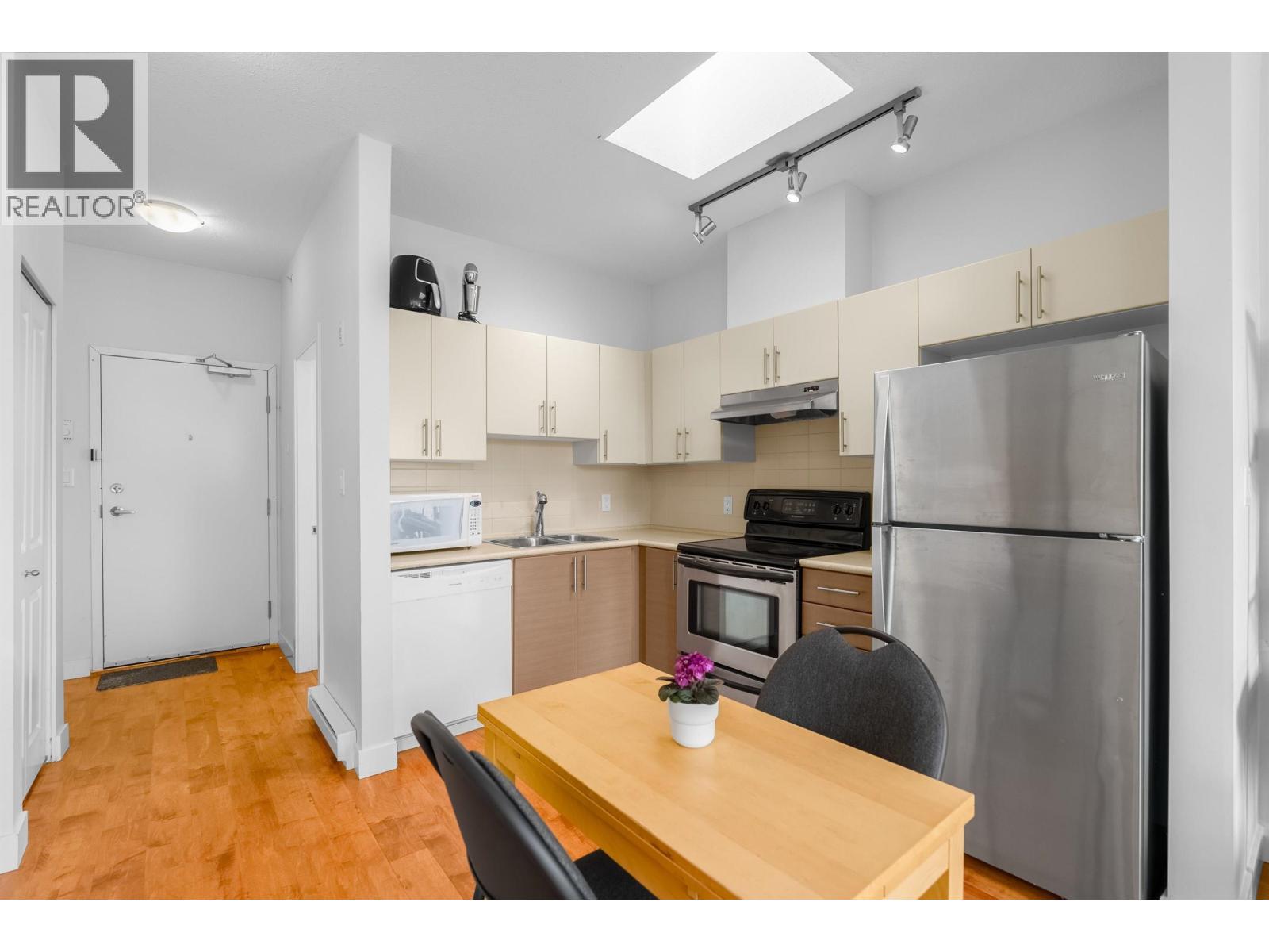 A kitchen with a table and chairs in the foreground and a refrigerator in the background.